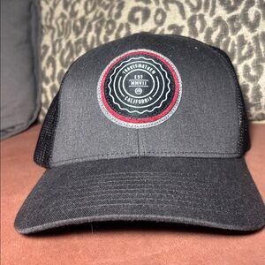 Travis Mathew Black and Red Logo Trucker Hat